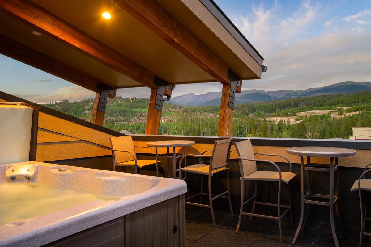 An elevated outdoor living area featuring a bubbling hot tub, modern outdoor seating, and sweeping views of the Rockies. The space is ideal for both daytime relaxation and starlit evenings, with a harmonious blend of luxury and natural beauty.