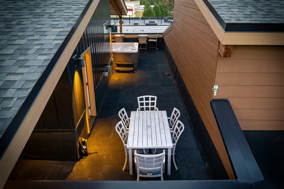 An inviting exterior dining space featuring a table with chairs and a barbecue grill on a patio. The setup overlooks natural surroundings and is perfect for social gatherings, sunset dinners, or starry nights outdoors. The mood is relaxed and welcoming, ideal for enjoying warmer months.
