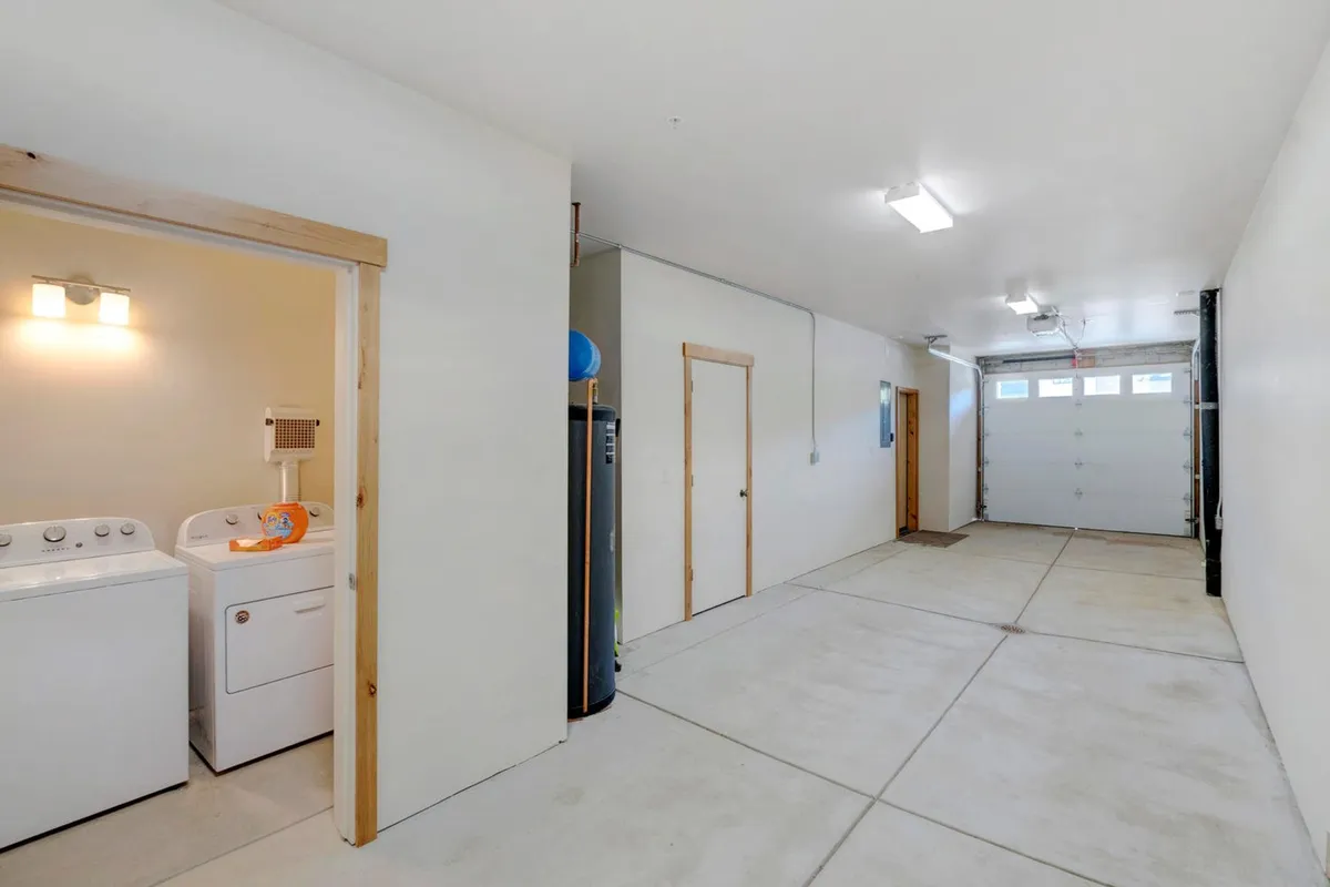 This interior shows a clean, practical garage space with a washer and dryer, garage door, utility door, and a water heater. The open area suggests ample room for both vehicles and organized storage, with visible cues of utility and efficiency, aligning with the section's focus on gear storage, parking, and adventure prep.