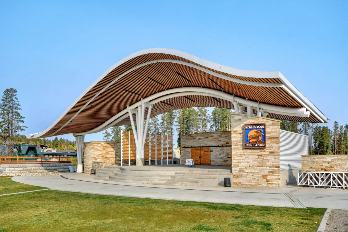 This image captures the curved roof structure and stone facade of an outdoor stage area, with an open space that hints at community events and gatherings.